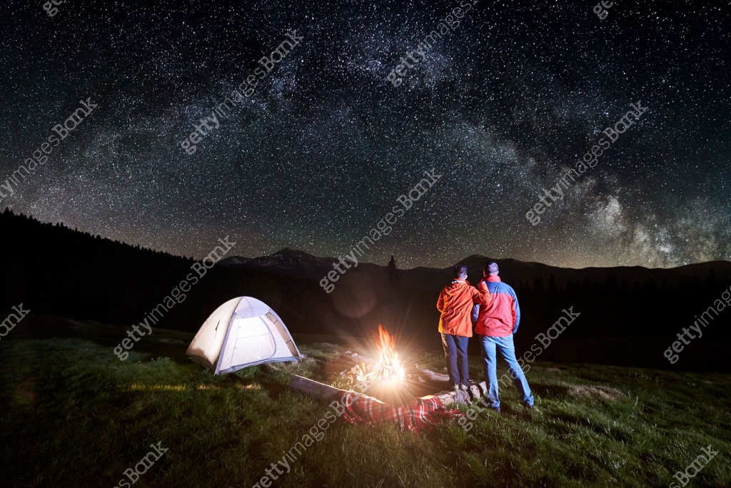 Banked Campire Night camping in the mountains. Rear view of romantic couple tourists ...