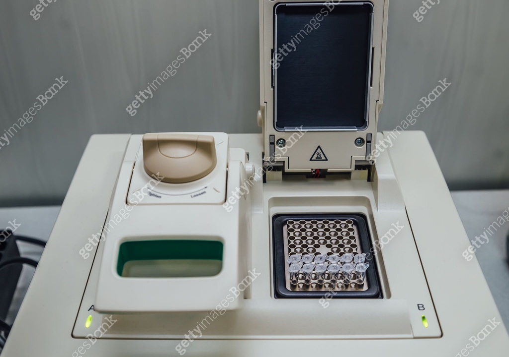 Opened polymerase chain reaction (PCR) cycler machine with DNA samples ...