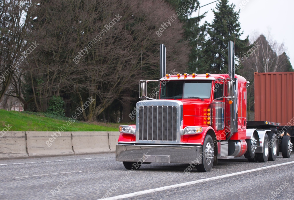 Bright red classic big rig semi truck transporting container on flat ...