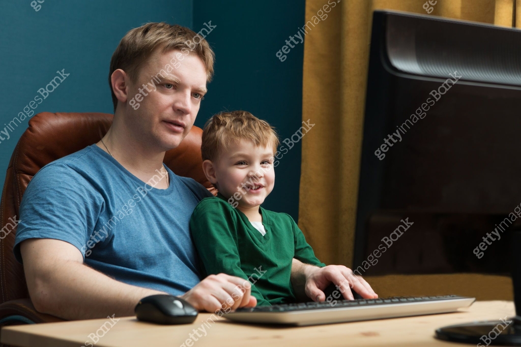 Father and little son using computer at home. The father with the son ...