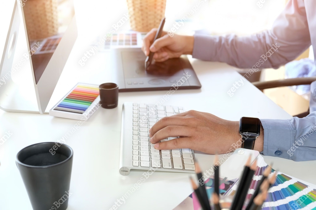 Graphic designer working on computer while using graphic tablet at desk ...