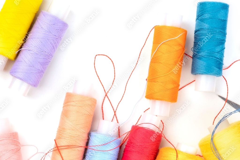 Overhead photo of thread spools of various colors on white with a place ...