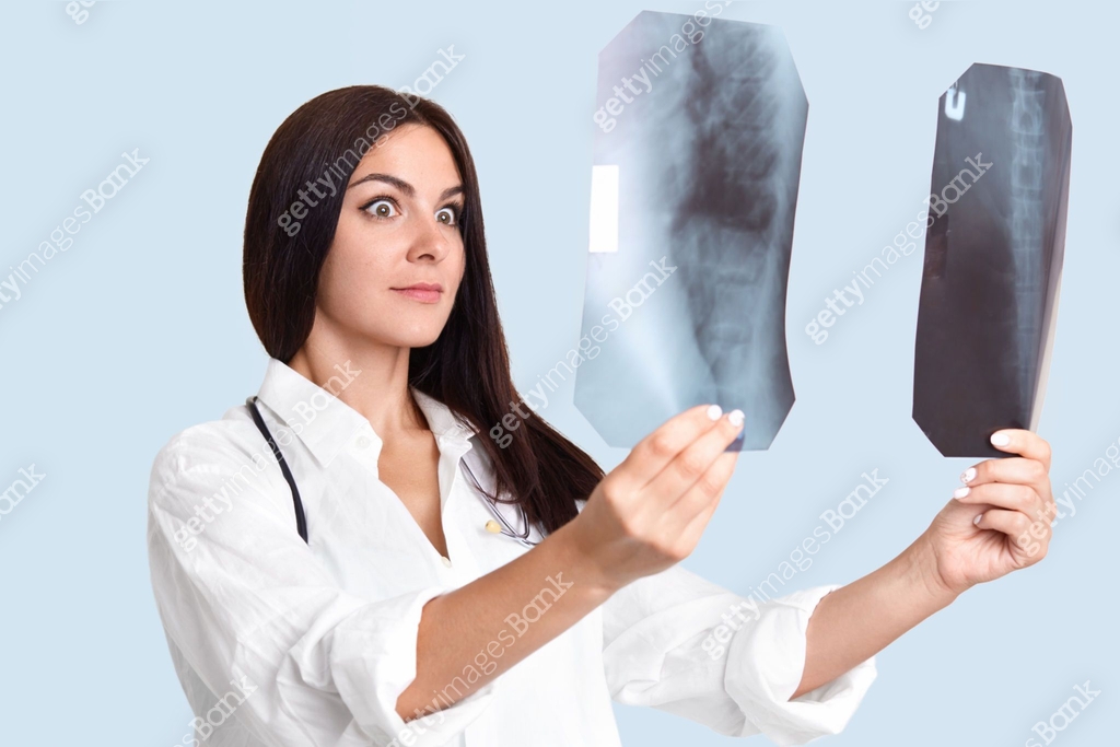Professional female radiologist with surprised expression, compares two ...