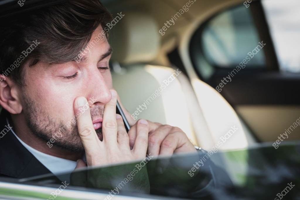 Overworked Business Executive talking on the phone while being driven ...
