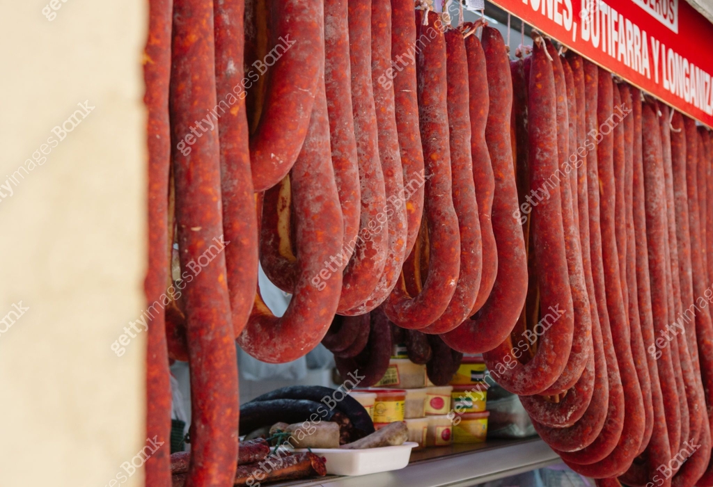 Huge loops of cured meat sausage hang from a butcher's counter in Cadiz ...