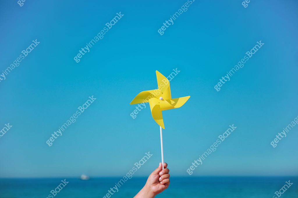 Hand holding yellow pinwheel in the sea 이미지 (1153547116) - 게티이미지뱅크