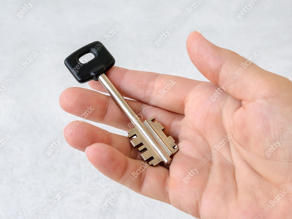 Large house key with black head lies on the open palm of a caucasian ...