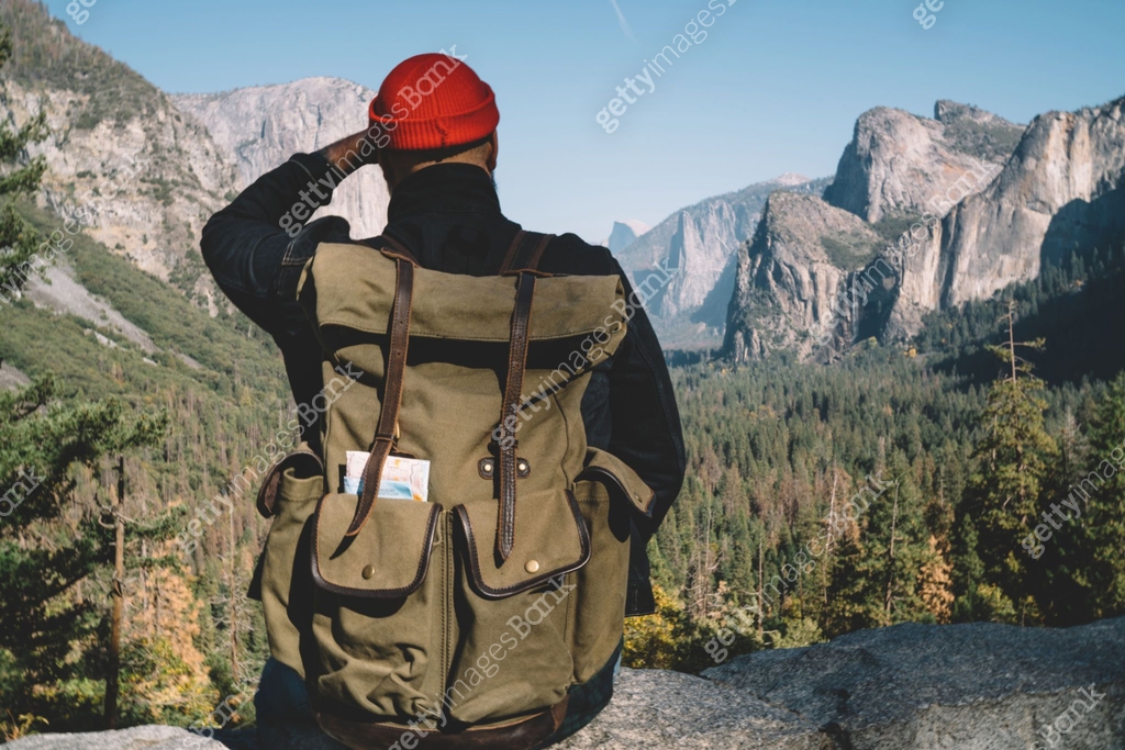 Back view of male traveler sitting on view point observing beautiful ...