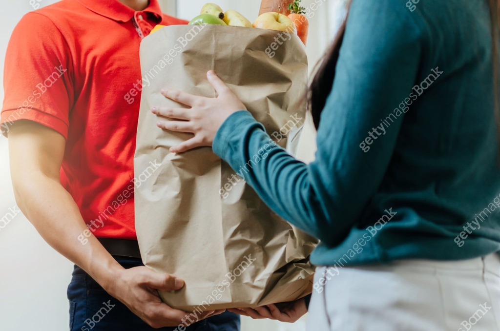 Fast Food Recipient smart food delivery service man in red uniform handing fresh food to ...
