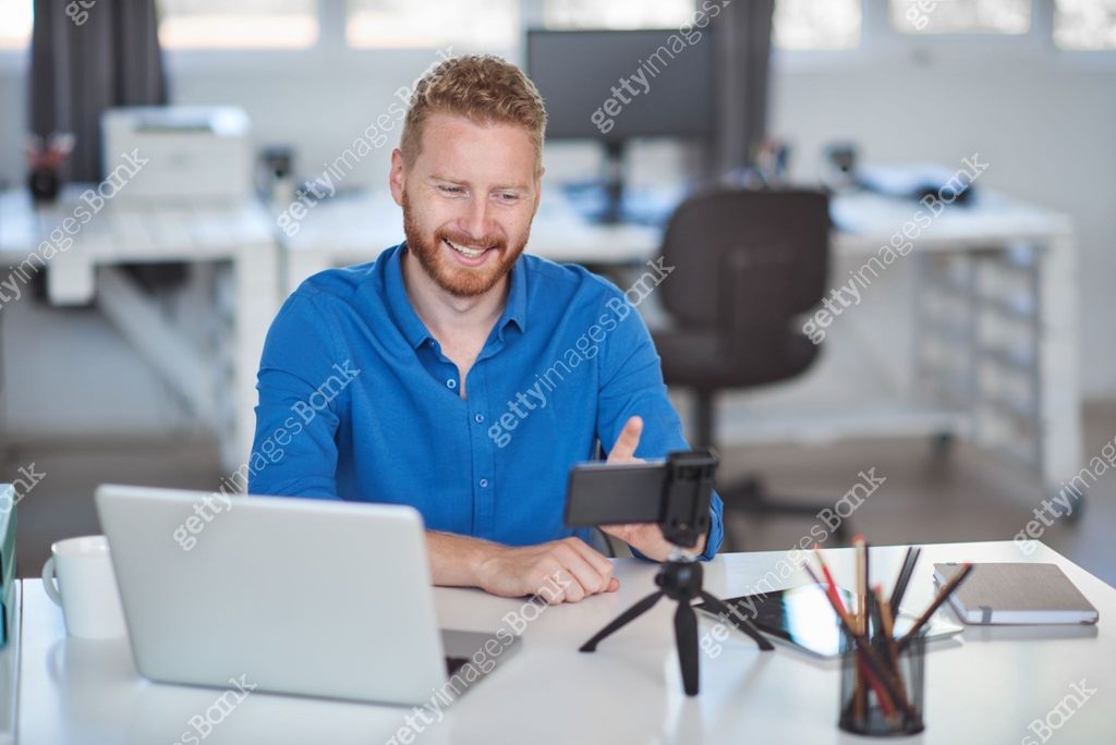Employee having video call over smart phone while sitting in office ...