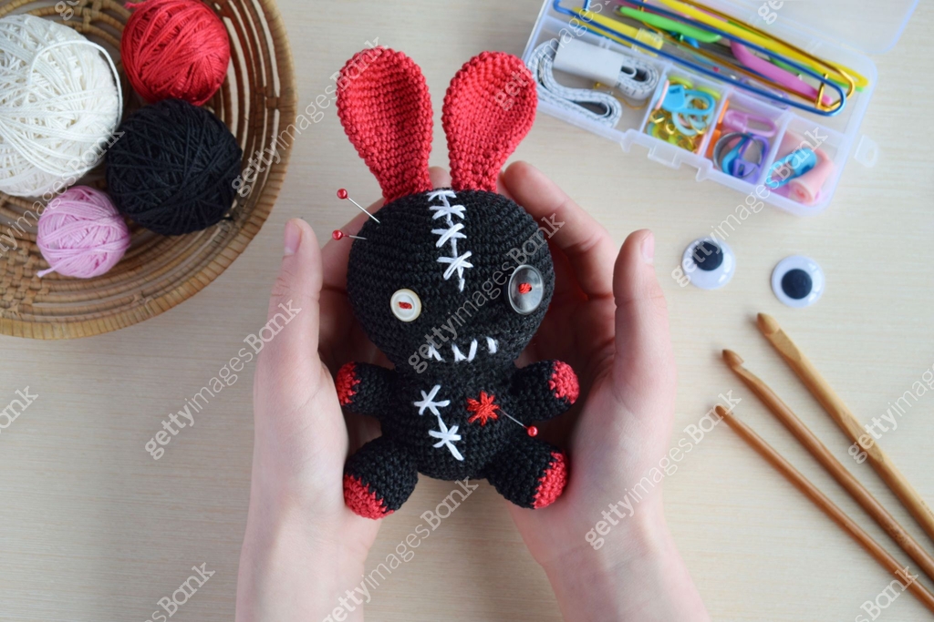 Making crochet voodoo rabbit. Toy for Halloween. On the table threads ...