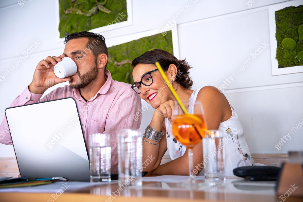 Couple of young relaxed people preparing blog together using free wifi ...