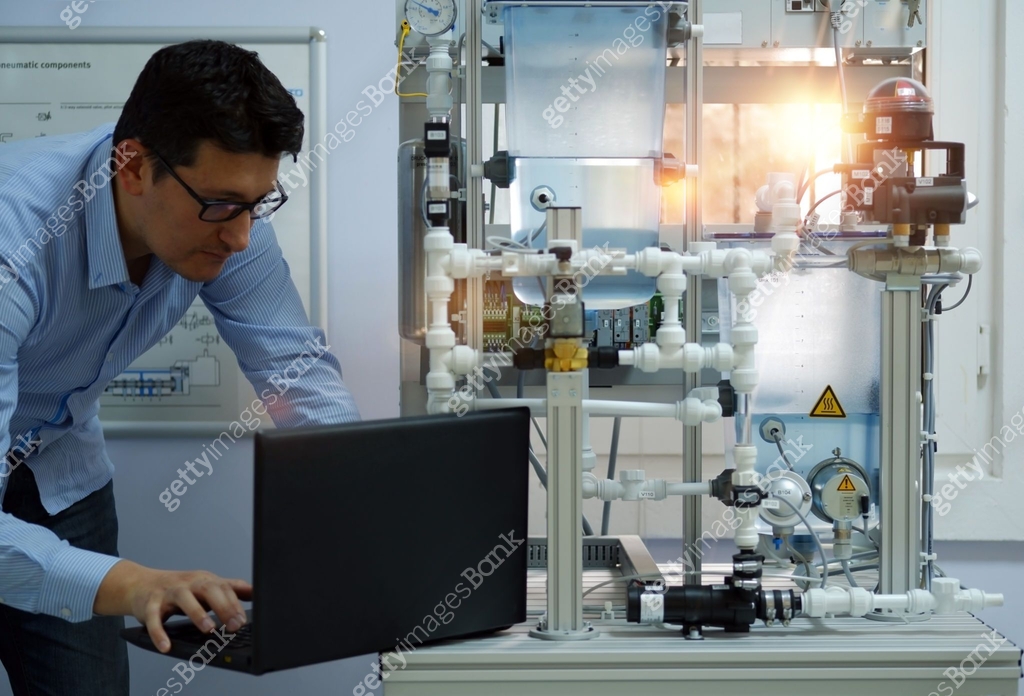 Focus on Engineer who is programming PLC with laptop for an analog ...
