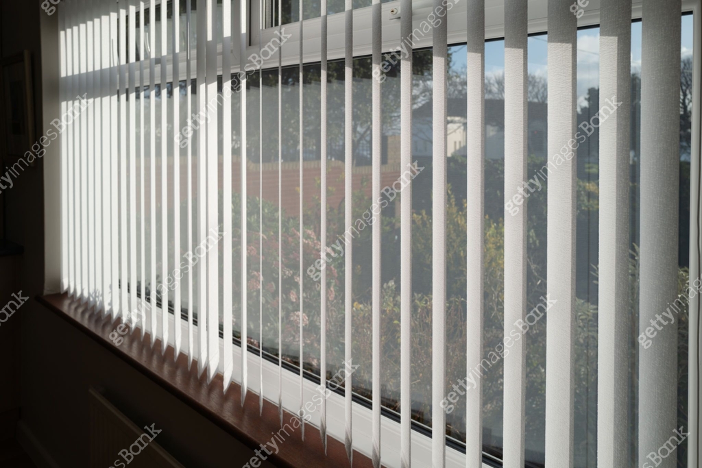White vertical blinds slats hanging in front of double glazed white ...