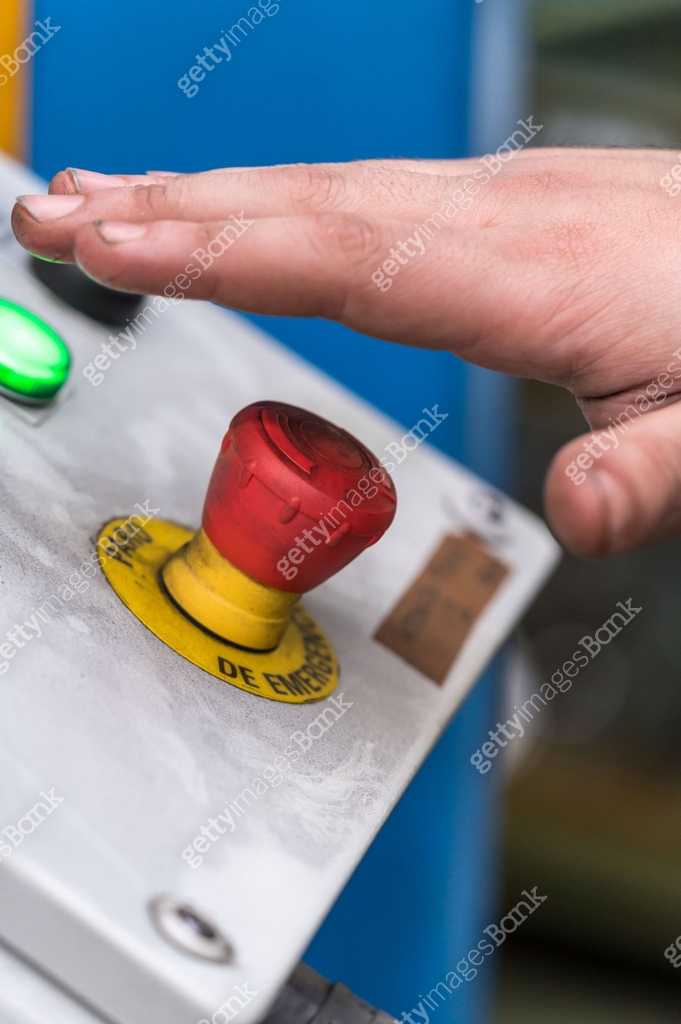 Hand pressing the red emergency button or stop button for industrial ...