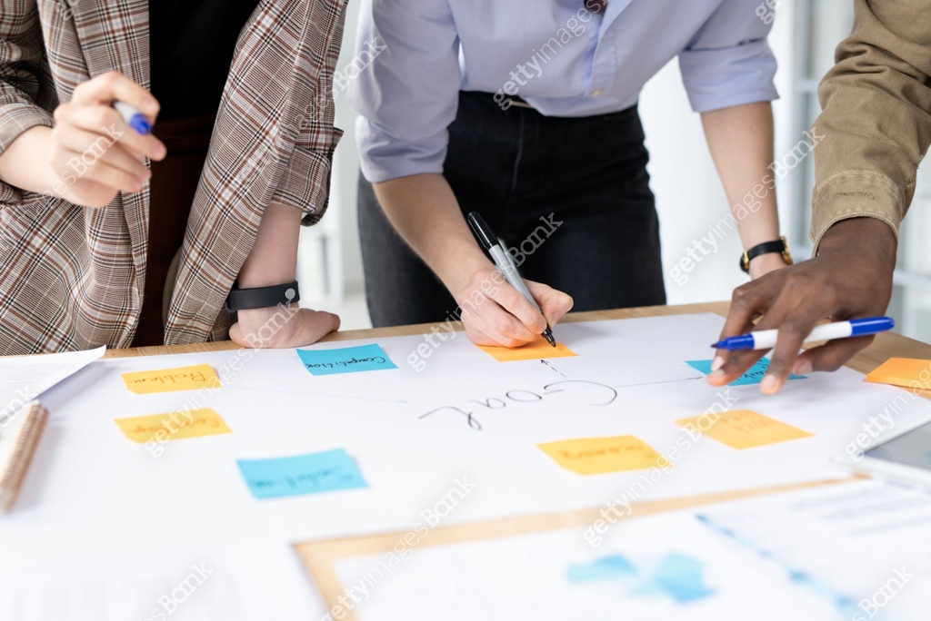 Working Notes Image One of three young colleagues making working notes on notepaper at ...