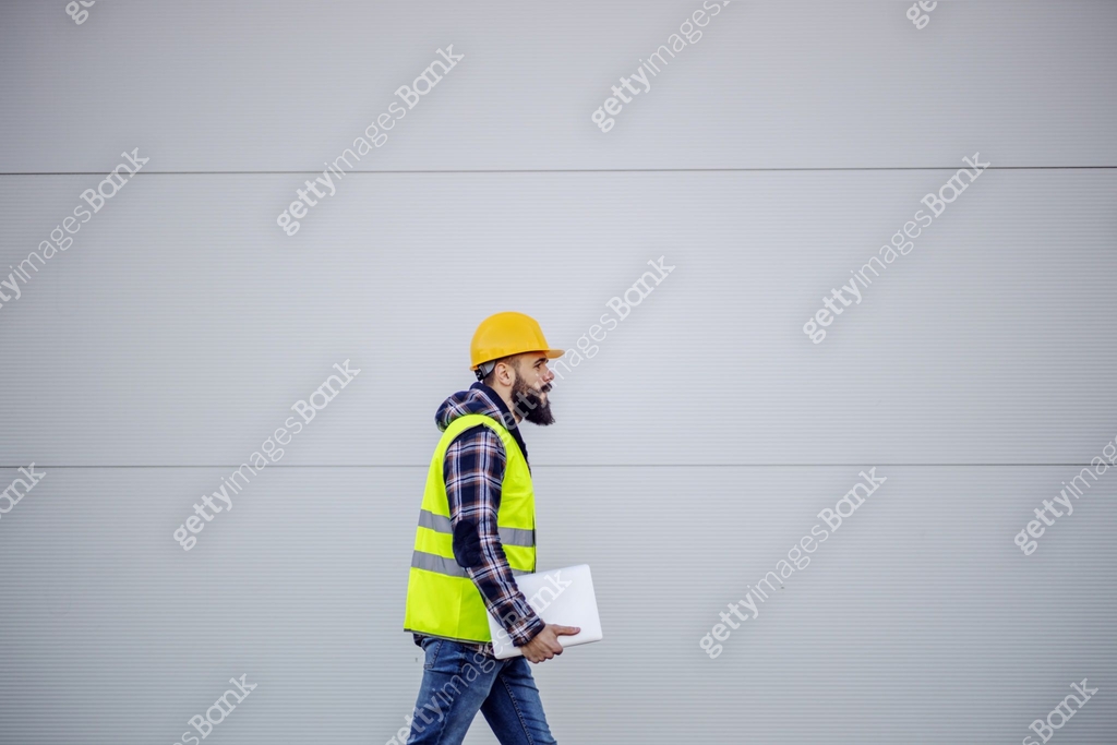 Side view of hardworking construction worker with safety helmet on head ...