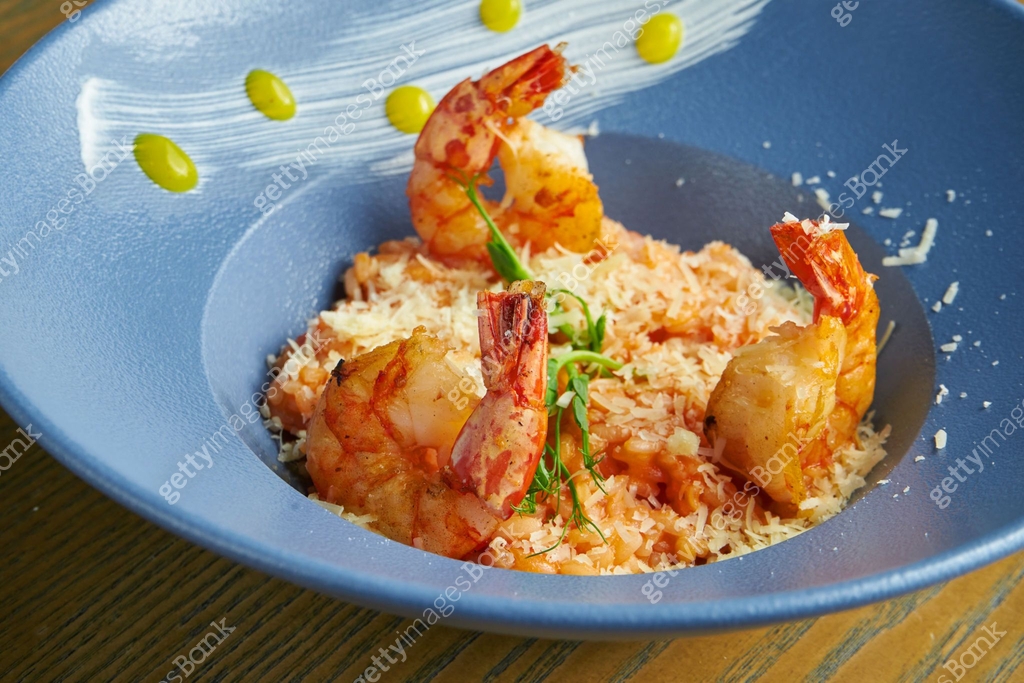 Risotto of rice with shrimps. Rice with seafood in a blue bowl against ...