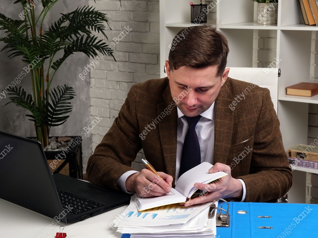 Man in suit making notes while working with financial charts and ...