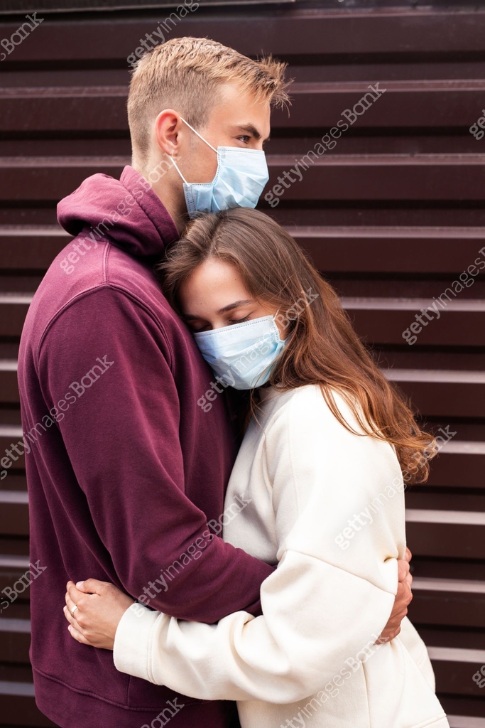 Young couple hugging each other with protective medical masks outdoor ...