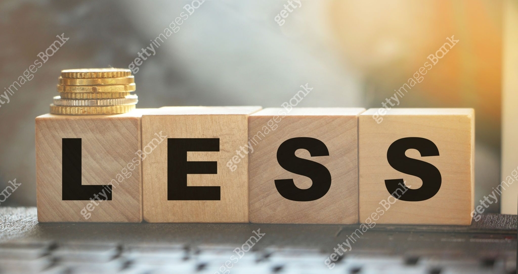 Less word on wooden cubic blocks with letters and stack of coins on it ...