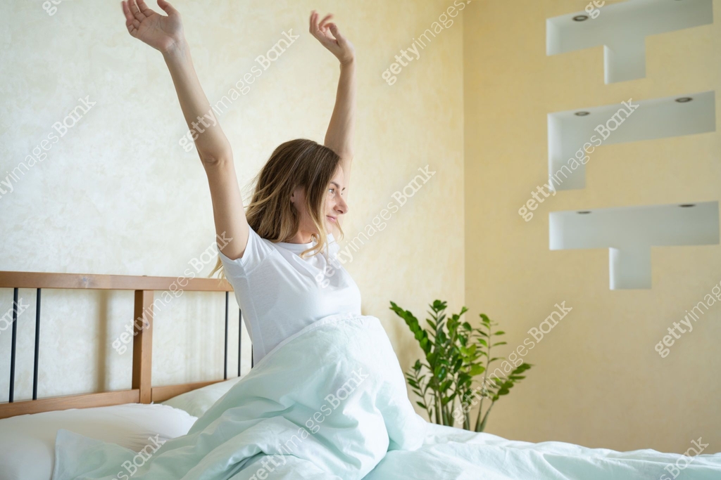 Woman waking up in her bed fully rested. Woman stretching in bed after ...