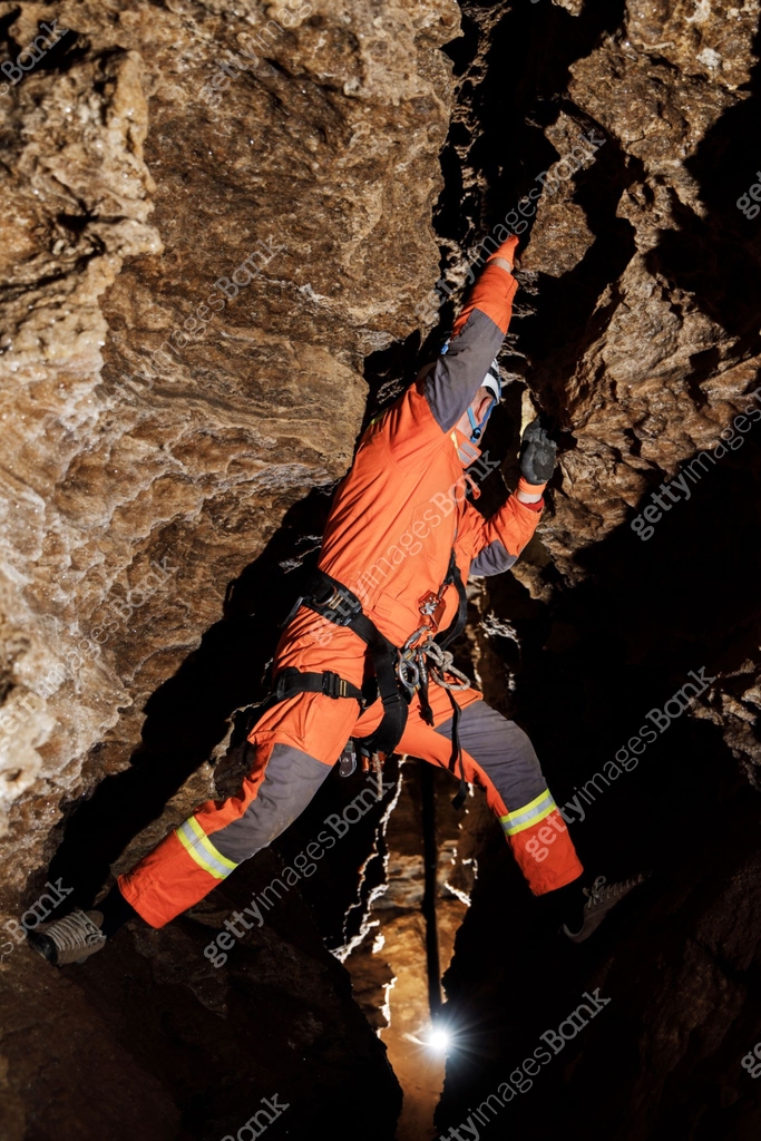 Guide Rope Cave Speleologist descend by the rope in the deep vertical cave tunnel. Cave ...