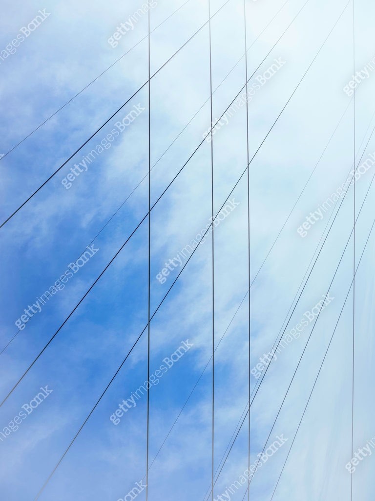 Tall image of abstract power lines and clouds on blue sky background ...
