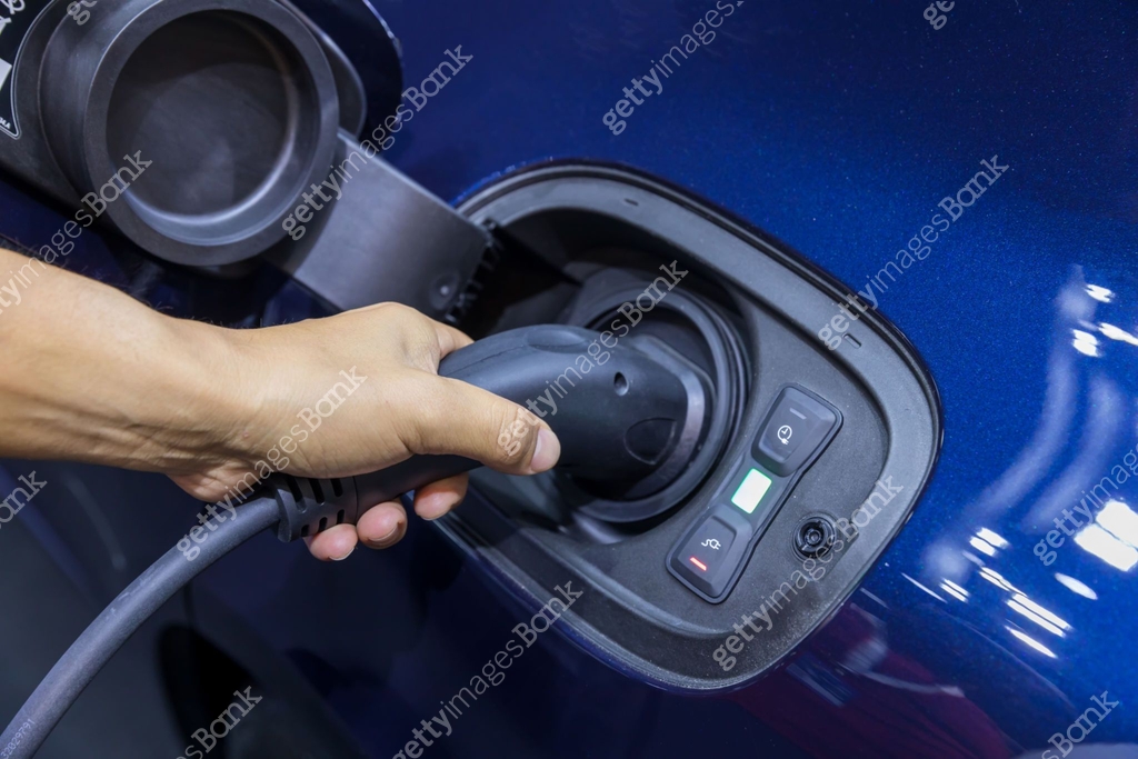 Hand holding Electric car charger. Electric Vehicle EV Charging station ...