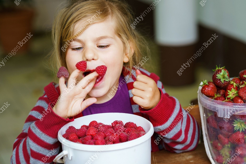 Portrait of happy little preschool girl eating healthy strawberries and ...