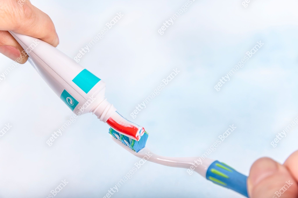 Toothpaste squeezed from tube onto brush, close up. Toothpaste being ...