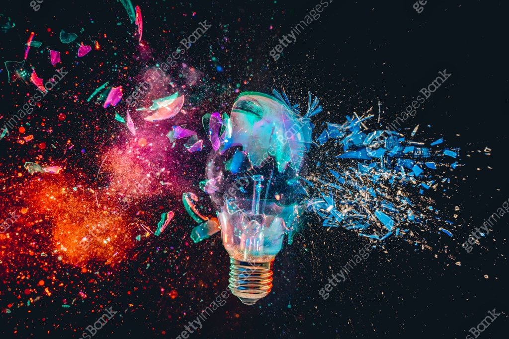 Light bulb exploding with colorful powder on black background ...