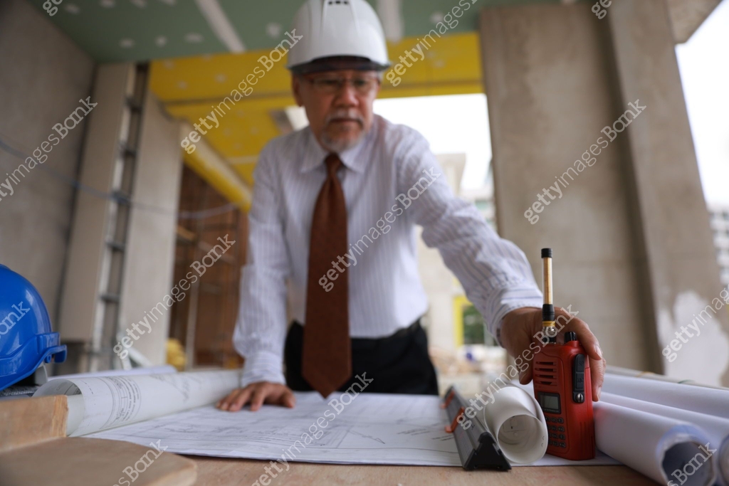 A senior project engineer man using building plans or drawings in the ...