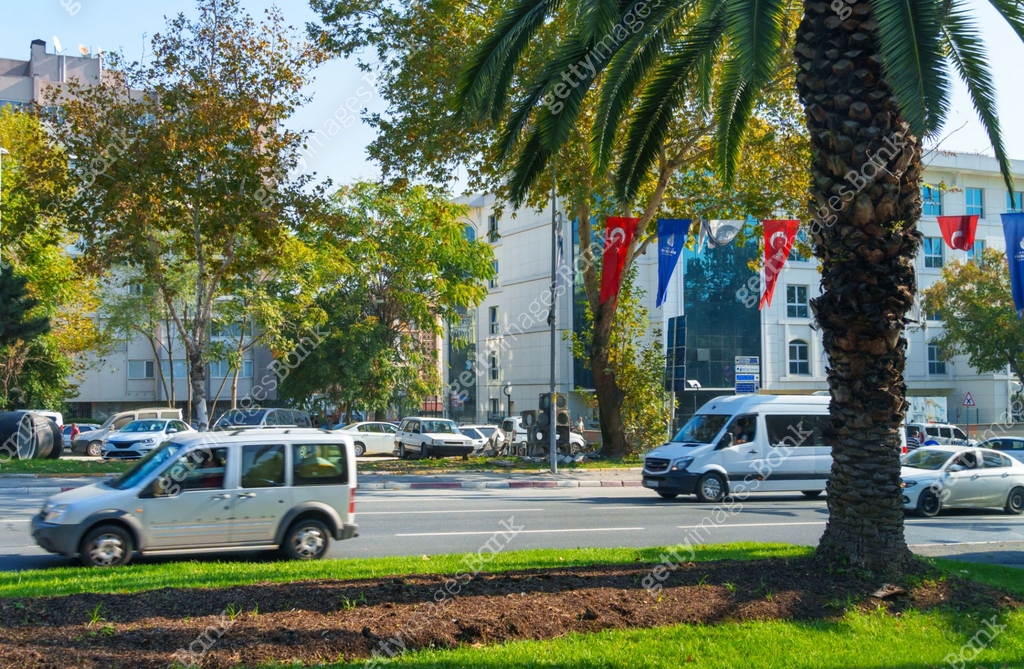 view of a city street with a road and cars, buildings and random people ...