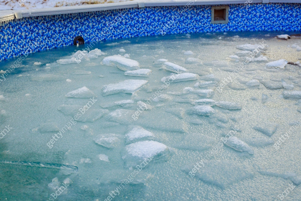 Pool Ice Frozen pool water with ice chunks and blue tiled surroundings in a cold ...