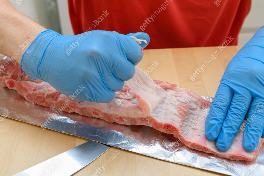 Chef removing the membrane from pork ribs before roasting, tasty ...