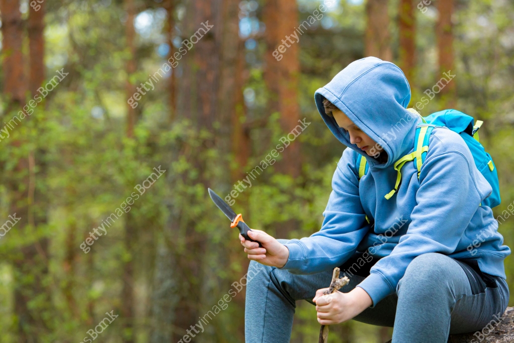 Teen Boy Sitting on Big Rock in Woods Making a Spear with Knife 이미지 ...