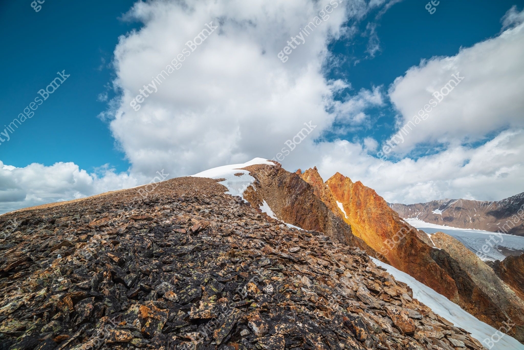 Snow Capped Ridge Snow-capped mountain ridge with cornice and red sharp rocks on top in ...