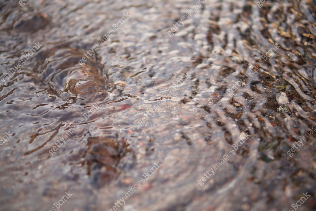 The camera captures a shallow stream of water flowing down the surface ...
