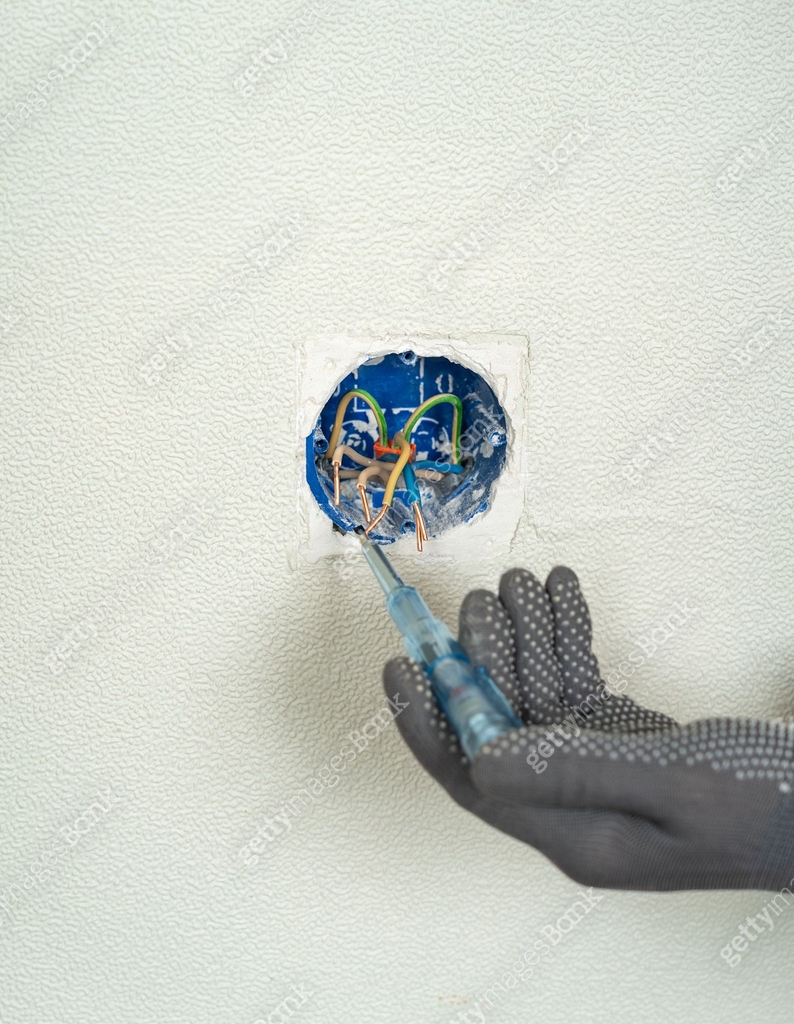 Hands check current in junction box with electrical wires using ...