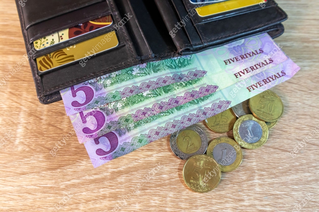 A brown leather wallet on the table with Saudi Arabian Riyal banknotes ...