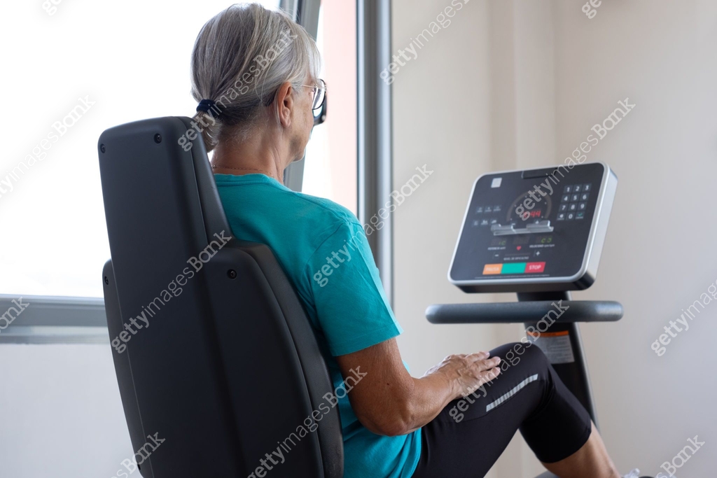 Rear view of Athletic senior woman enjoying stay fit working in gym ...