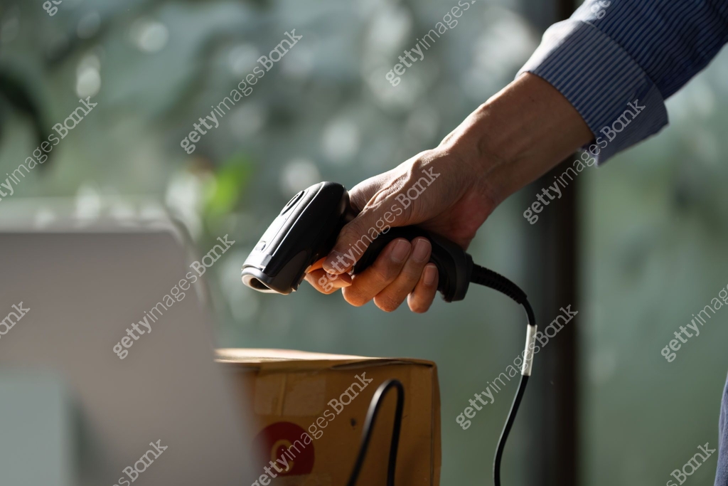 Owner Scan Focused small business owner using a handheld barcode scanner to ...