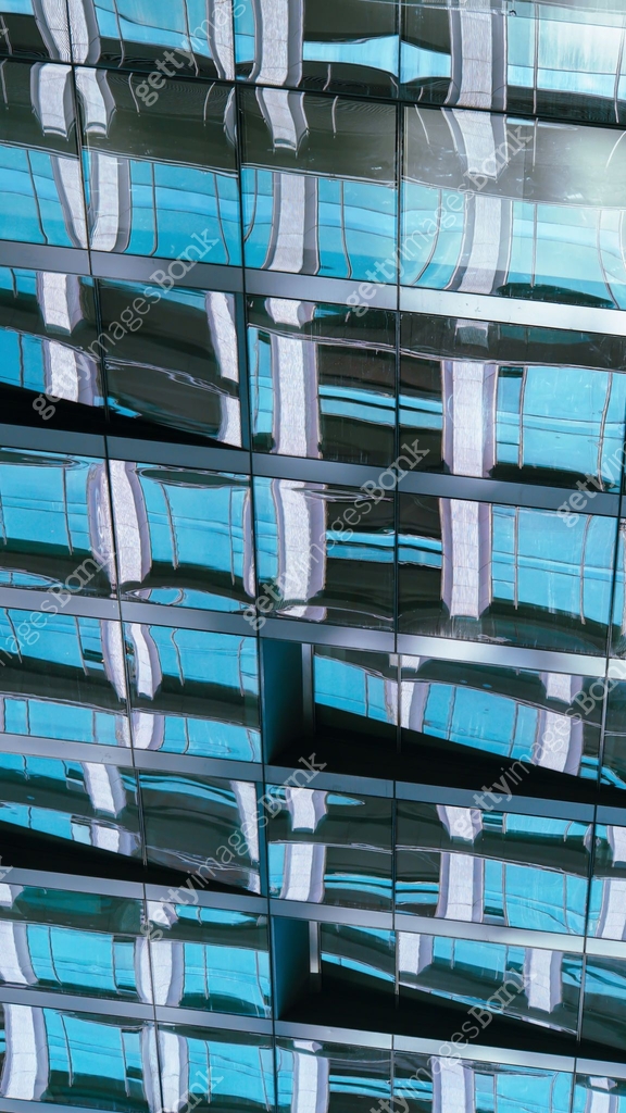 A distorted reflection of a modern building on its glass facade creates ...