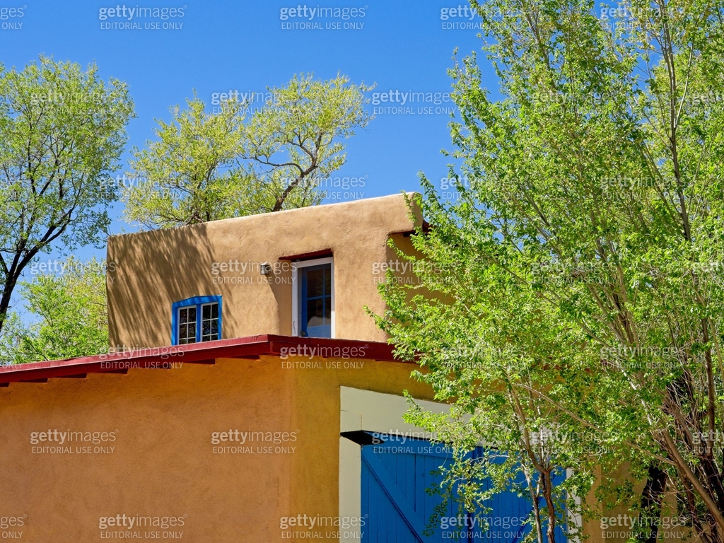 Adobe structure roofline with green tree and blue sky background in ...