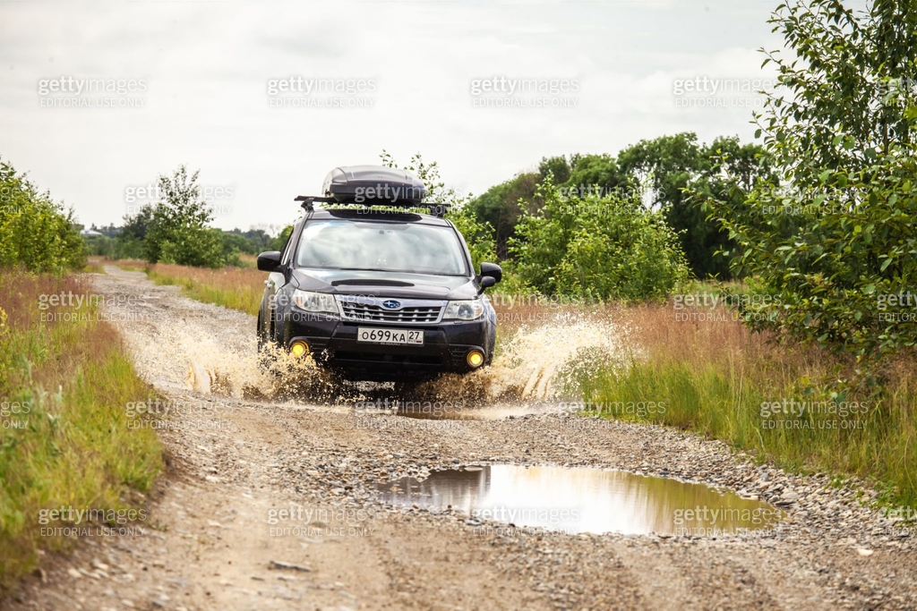 Black Subaru Forester Driving On A Dirt Road With Puddles black-subaru-forester-driving-on-a-dirt-road-with-puddles