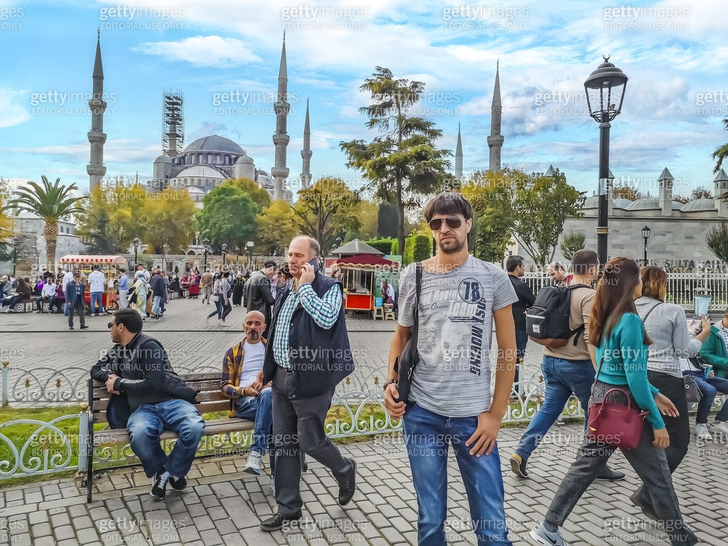 Many people walk and sit on benches in Sultanahmet Square on the ...