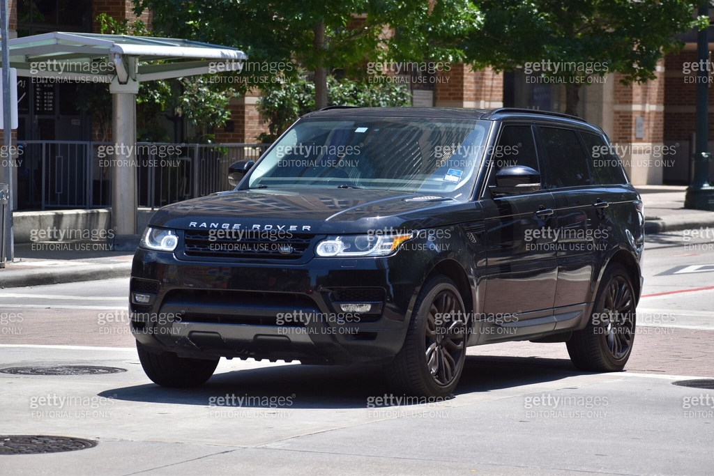 A portrait of a black Land Rover Range Rover SUV cruising in a downtown ...