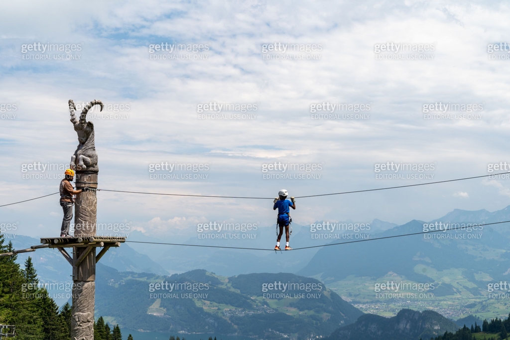 Child walks on the ropes course as a guide watches for his safety at ...