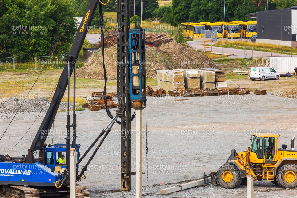 Construction site with heavy machinery performing foundation work ...